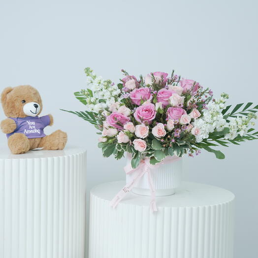 Нежно-розовые цветы в белом керамическом горшке и плюшевый мишка