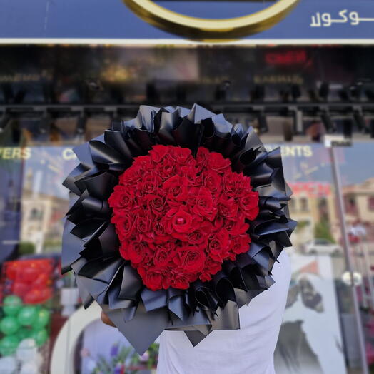 Массивный букет красных роз в матовой чёрной упаковке
