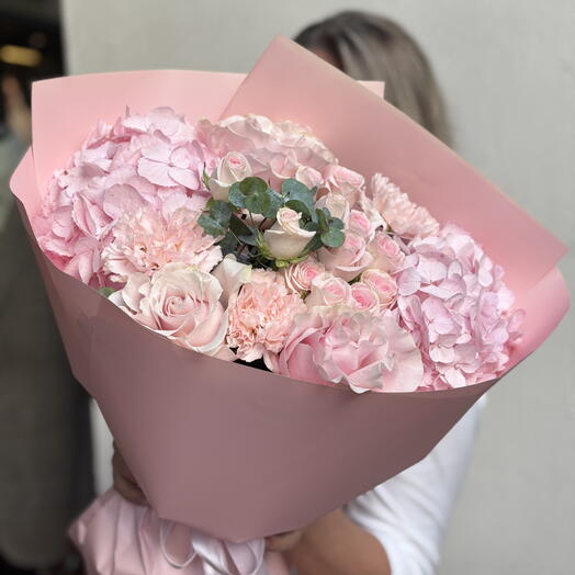 A bouquet of pink hydrangeas, carnations, and eucalyptus