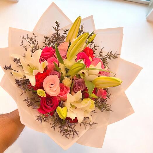 Сказочный букет из смешанных цветов – розы, лилии и эустомы, связанные вручную, в мягкой пастельной упаковке