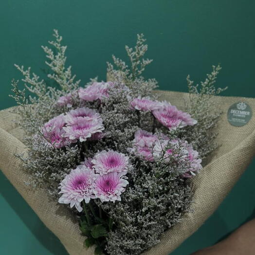 Bouquet rose embelli _limonium gris violacé enveloppé dans un tissu blanc cassé