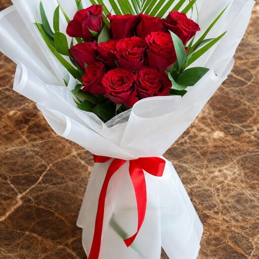 باقة أنيقة من الورود الحمراء مع خضرة استوائية