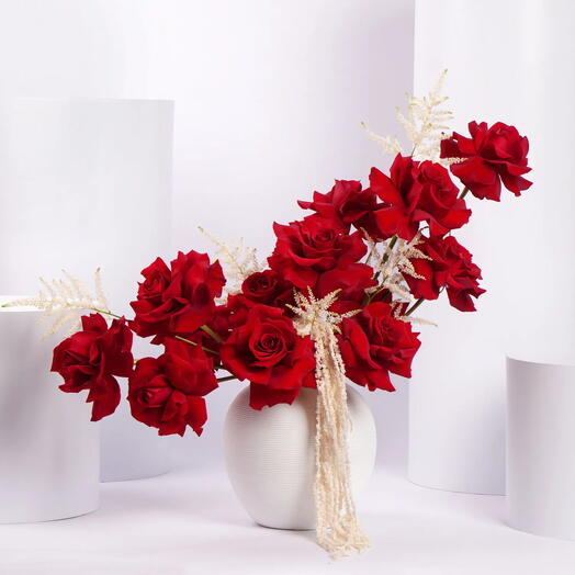 Arrangement floral de roses rouges dans un vase en céramique blanc