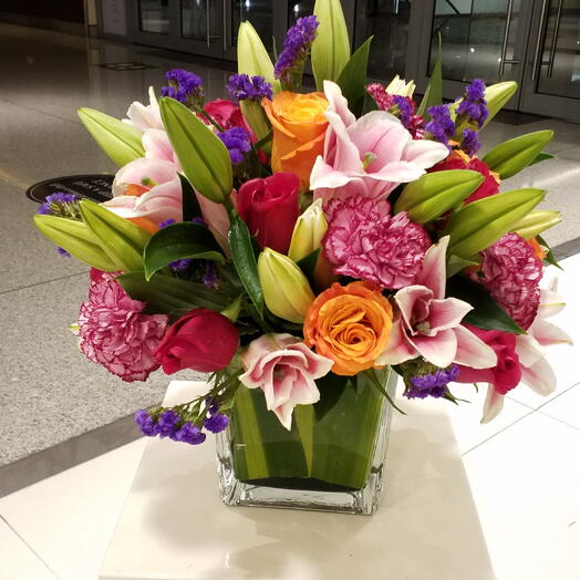 Элегантная смешанная цветочная композиция из лилий и роз в стеклянной вазе