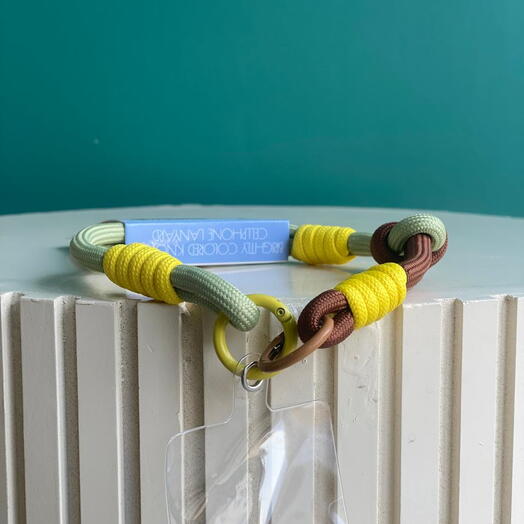 Ярко окрашенный шнурок для мобильного телефона с узлами в жёлтом, коричневом и лимонно-зелёном.